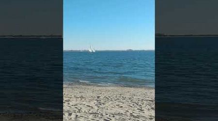 Ocean waves, sun, yachts and boulders on Manhattan Beach in Brooklyn, New York